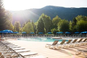 a pool with lounge chairs and umbrellas on a resort at Camping RCN Belledonne in Le Bourg-dʼOisans