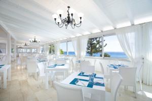 un comedor con mesas blancas y sillas blancas en Nicolaus Club Quattro Lune Resort, en Cala Liberotto