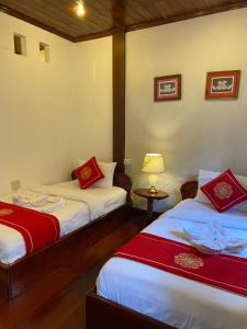um quarto com duas camas e uma mesa com um candeeiro em Soutikone Place House 2 em Luang Prabang