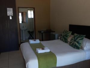 a hotel room with a bed with towels on it at OR Tambo Guest House in Kempton Park