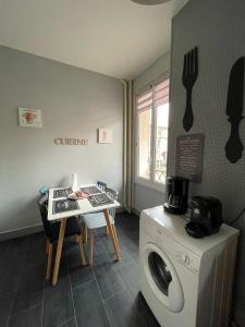 a kitchen with a washing machine and a table at Les Cocons de Stéphanie in Vichy