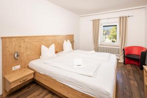 een slaapkamer met een groot wit bed en een rode stoel bij Mentenwirt Pension&Appartements in Sankt Martin