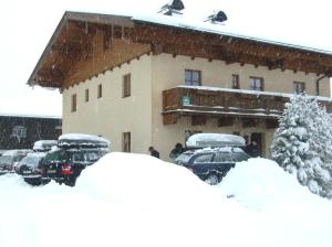 a group of cars parked outside of a building in the snow at Libiseller Anita Biobauernhof UNTERHUB in Taxenbach
