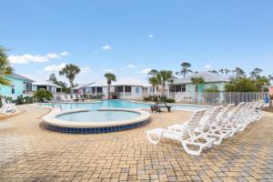 un grupo de tumbonas blancas alrededor de una piscina en Barefoot Bungalow at Rookery, en Gulf Shores