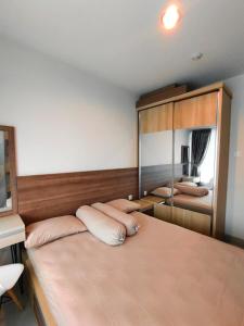 1 dormitorio con cama con almohadas y espejo en Grand Kamala Lagoon By Paris Properti, en Rawapanjang