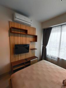 1 dormitorio con 1 cama, TV y ventana en Grand Kamala Lagoon By Paris Properti, en Rawapanjang