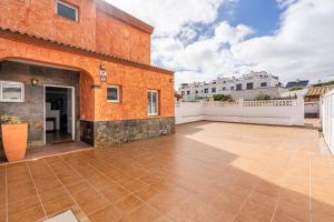 un patio al aire libre con un edificio de color naranja y una valla blanca en Villa Paraíso, en Corralejo