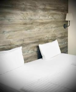 - 2 oreillers blancs sur un lit avec un mur en bois dans l'établissement Check-in Hamburg, à Hambourg