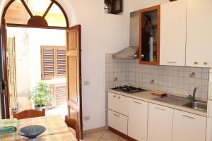 a kitchen with white cabinets and a table and a window at Appartamenti Stella in Lipari