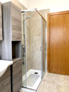 La salle de bains est pourvue d'une douche avec une porte en verre. dans l'établissement La Cicala - appartamento con giardino privato, à Rivoli Veronese