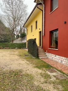 une maison jaune et rouge avec une cour dans l'établissement La Cicala - appartamento con giardino privato, à Rivoli Veronese