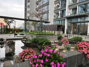 einen Garten mit rosa Blumen vor einem Gebäude in der Unterkunft Vinhomes Metropolis 1Br Mai-homestay in Hanoi