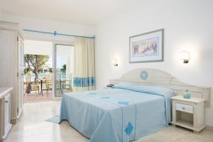 a bedroom with a bed and a view of a patio at Nicolaus Club Quattro Lune Resort in Cala Liberotto +41 photos
