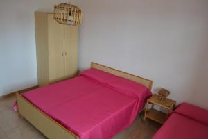 a bedroom with a pink bed and a small table at Apt 7 Posti Vicino Spiaggia in San Foca