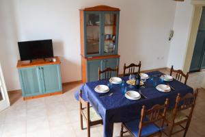 uma sala de jantar com uma mesa azul com cadeiras e uma televisão em Apt 7 Posti Vicino Spiaggia em San Foca