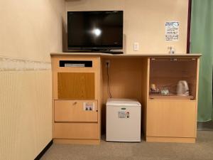 Habitación con nevera pequeña y escritorio con TV. en ホテルSpace24, en Miyakonojō