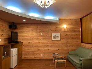 sala de estar con paredes de madera y sofá verde en ホテルSpace24, en Miyakonojō