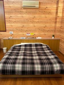 Cama en habitación con pared de madera en ホテルSpace24, en Miyakonojō
