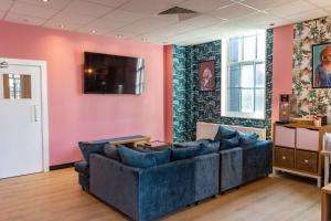a living room with a couch and a tv on a pink wall at Hostelle - women only hostel London in London