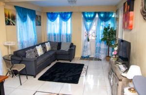 uma sala de estar com um sofá e cortinas azuis em PRI Guest House em Arnos Vale