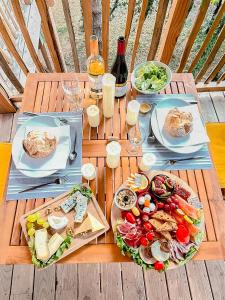 une table en bois avec deux assiettes de nourriture dans l'établissement Cabane Château hôtel luxe avec spa privatif Aulteribe - Le Peydébé, à Vieille-Brioude