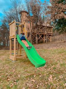 un toboggan vert sur une aire de jeux dans une cour dans l'établissement Cabane Château hôtel luxe avec spa privatif Aulteribe - Le Peydébé, à Vieille-Brioude