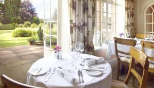 a table with wine glasses on it in a restaurant at Trigony House Hotel and Garden Spa in Closeburn