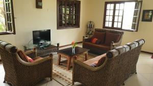 sala de estar con sillas de mimbre y TV en Secluded luxury villa with pool views privacy en Rivière Noire