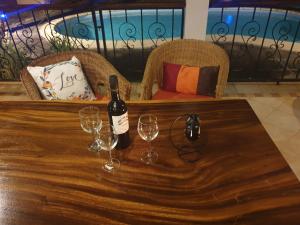 una botella de vino sentada en una mesa con copas de vino en Secluded luxury villa with pool views privacy en Rivière Noire