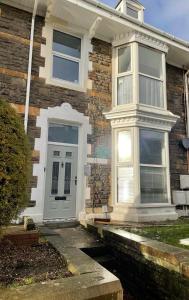 a brick house with a white front door and aphalt at Stunning Flat Close to Beach in Swansea