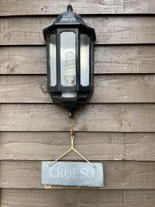 a street light hanging on a wooden wall with a sign at 5 Star Shepherds Hut in Betws y Coed with Mountain View in Capel-Curig
