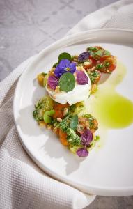 un plato blanco con una ensalada con una flor. en Feriendomizil & Weingut Roussel mit Restaurant "La Bonne Adresse", en Bernkastel-Kues