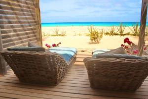 - une terrasse couverte avec 2 chaises en osier et la plage dans l'établissement Villa Cristina Alojamento, Praia de Chaves, Boa Vista, Cape Verde, WI-FI, à Sal Rei