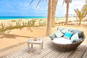 a wicker chair sitting on a deck next to the beach at Villa Cristina Alojamento, Praia de Chaves, Boa Vista, Cape Verde, WI-FI in Sal Rei