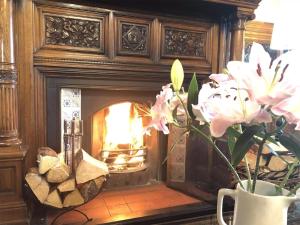 Mellington Hall Country House Hotel في Church Stoke: إناء من الزهور أمام موقد
