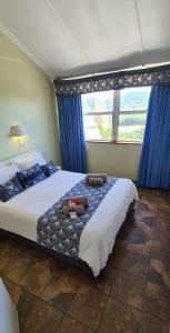a bedroom with a large bed with blue curtains and a window at Pearly Shells in Scottburgh