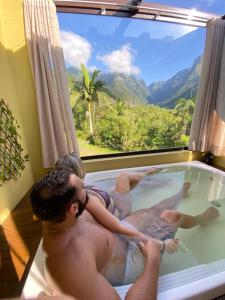 two men in a bath tub with a view at Refúgio Ecológico Pedra Afiada in Praia Grande