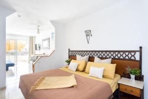 阿德耶Studio 50m from Puerto Colón Beach的卧室里有一张大床，上面有黄色枕头