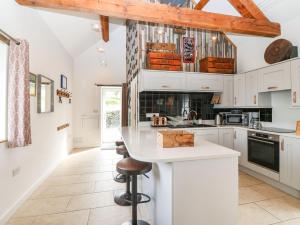 a kitchen with white cabinets and a counter with stools at Y Granar The Granary in Oswestry