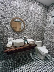 a bathroom with a sink and a toilet and a mirror at Mosquito Boutique Hotel Zona Colonial in Santo Domingo