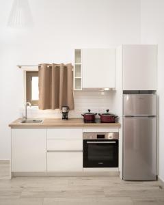 una cocina con armarios blancos y electrodomésticos de acero inoxidable en PETRINO FOINIKOUNTA en Finikounta