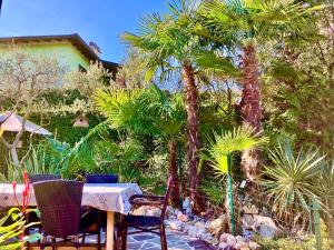 un tavolo e sedie in un giardino con palme di B&B Desenzano Paradise a Desenzano del Garda
