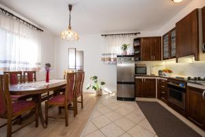 a kitchen with a table with chairs and a refrigerator at Apartman Elvis in Lovran