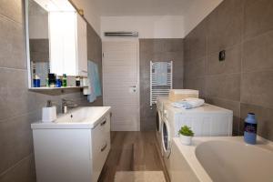 a bathroom with a sink and a tub and a washing machine at Apartman Elvis in Lovran +18 photos