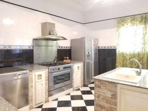 a kitchen with stainless steel appliances and a checkered floor at Appartement 200 m 2 + 5 min du c.c.o in Oran