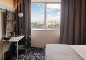 a hotel room with a bed and a desk and a window at ibis Bucharest Politehnica in Bucharest