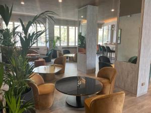 een lobby met tafels, stoelen en planten bij Hotel Embassy in Pero