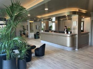 a woman sitting at a reception desk in a lobby at Hotel Embassy in Pero