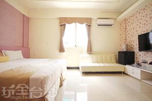 a bedroom with a bed and a couch and a tv at 伯爵四季休閒民宿 in Jinhu