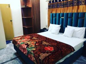 a bedroom with a bed with a colorful blanket on it at Hotel Air inn in Lahore